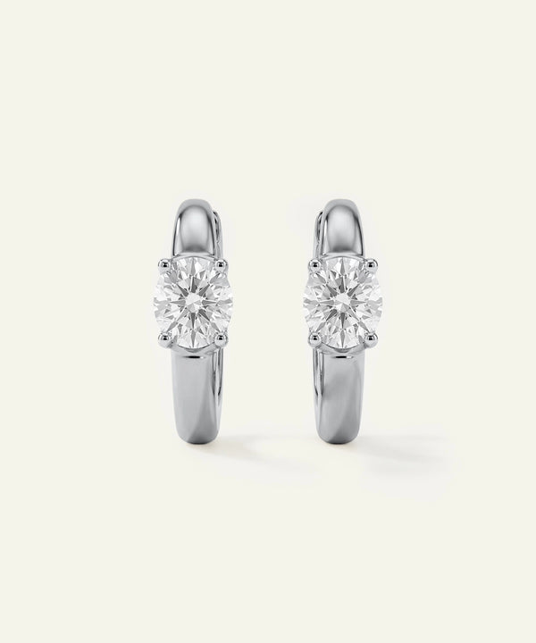 Pair of silver hoop earrings with clear gemstones on a white background