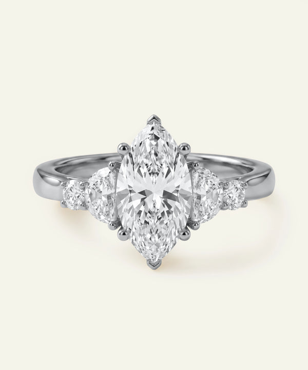 Diamond ring with pear-shaped center stone on a light gray background