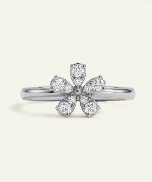 Silver ring with diamond flower design on a light gray background