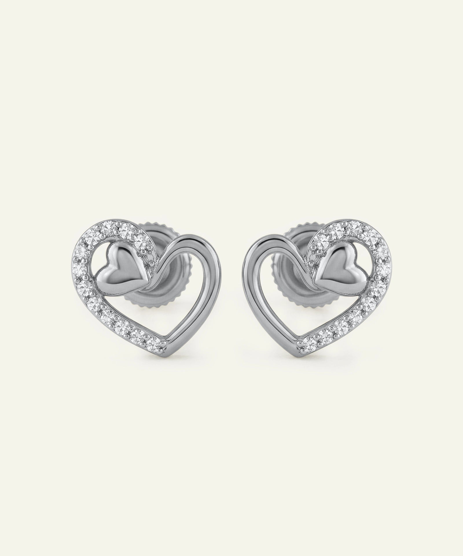 Pair of silver heart-shaped earrings with small diamonds on a white background