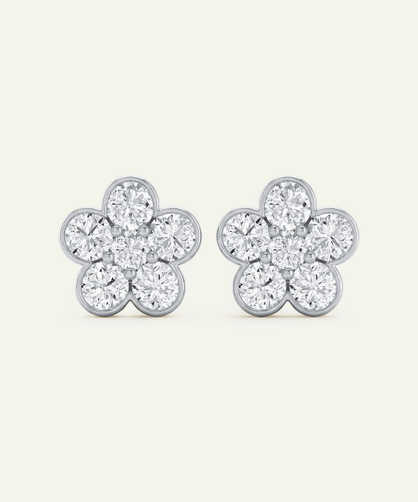 Pair of silver flower-shaped earrings with clear gemstones on a white background