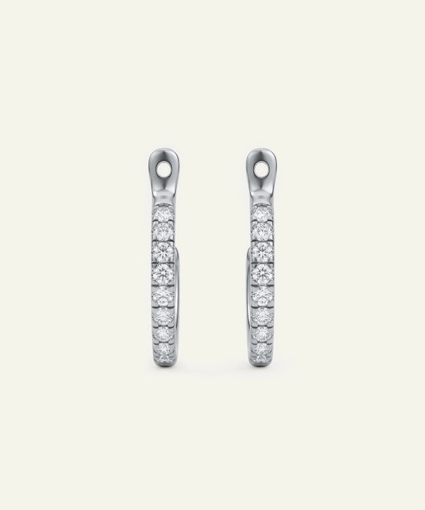Pair of silver earrings with clear gemstones on a white background