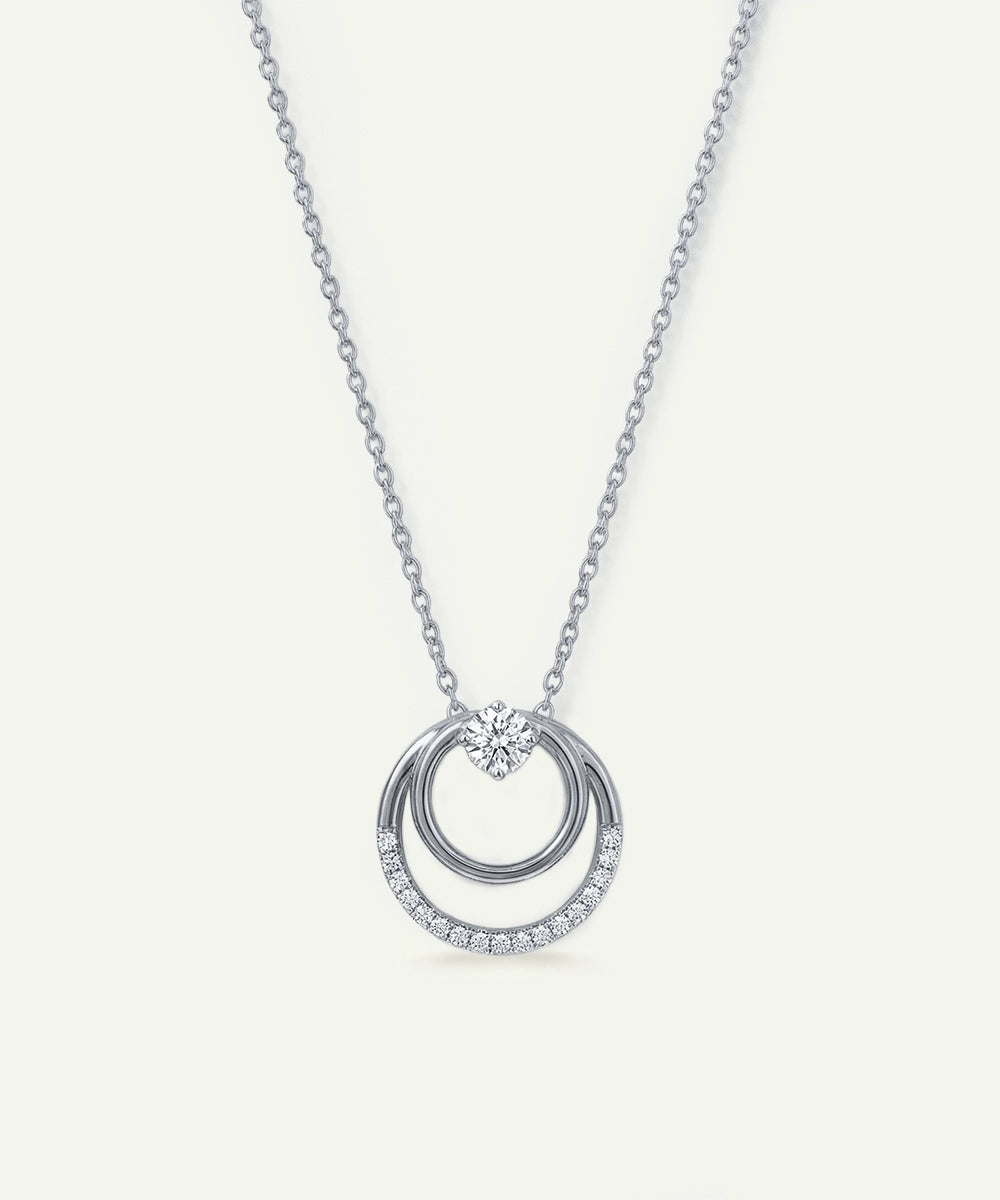 Silver necklace with a circular pendant on a light gray background