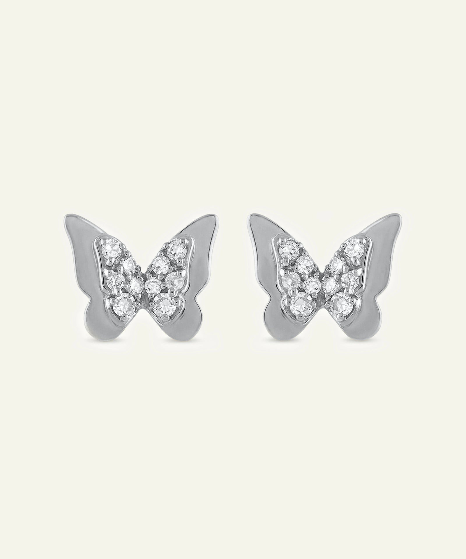 Butterfly-shaped earrings with gemstones on a light gray background