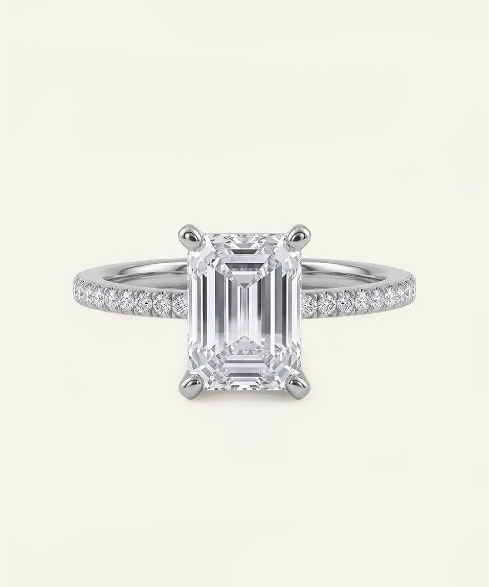 Diamond ring with emerald-cut center stone on a white background