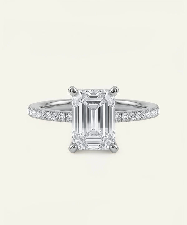 Diamond ring with emerald-cut center stone on a white background