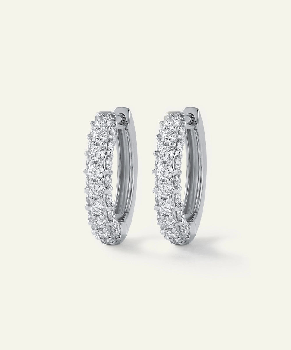 Pair of silver hoop earrings with clear gemstones on a white background