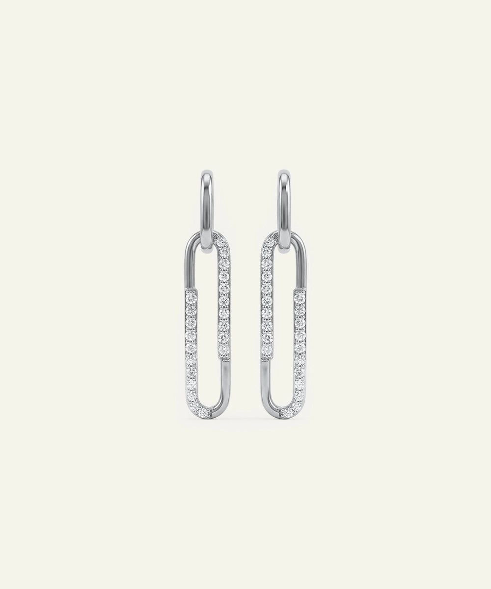 Pair of silver earrings with clear gemstones on a light gray background