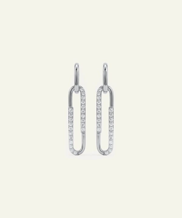 Pair of silver earrings with clear gemstones on a light gray background