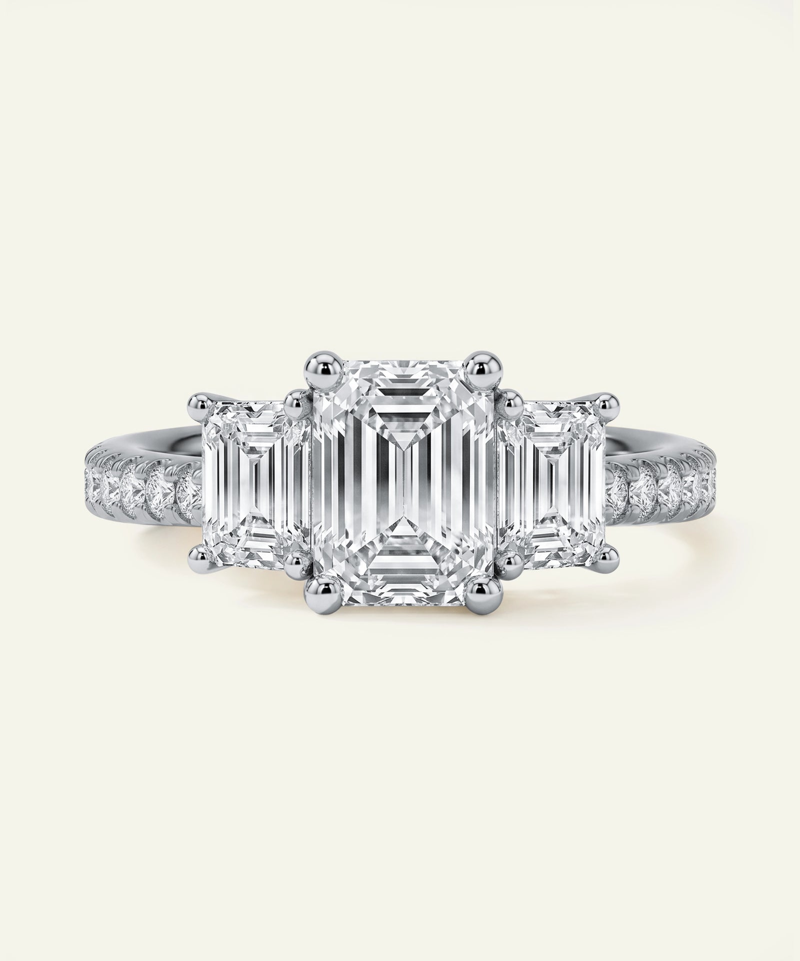 Diamond ring with emerald-cut center stone and smaller diamonds on a light grey background