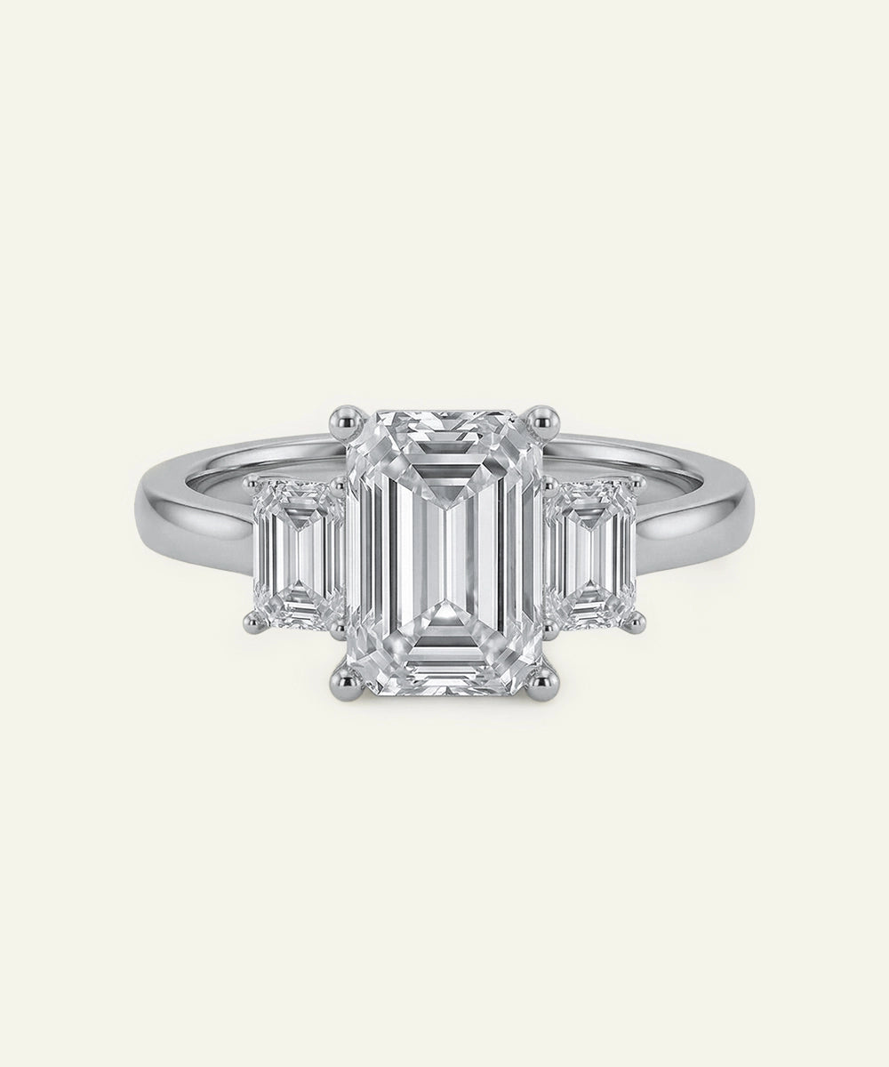 Diamond ring with emerald-cut stones on a white background