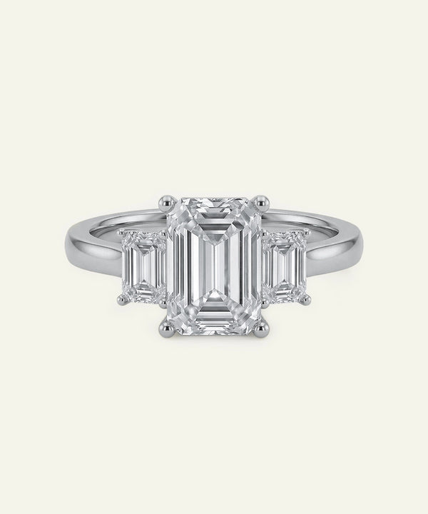Diamond ring with emerald-cut stones on a white background