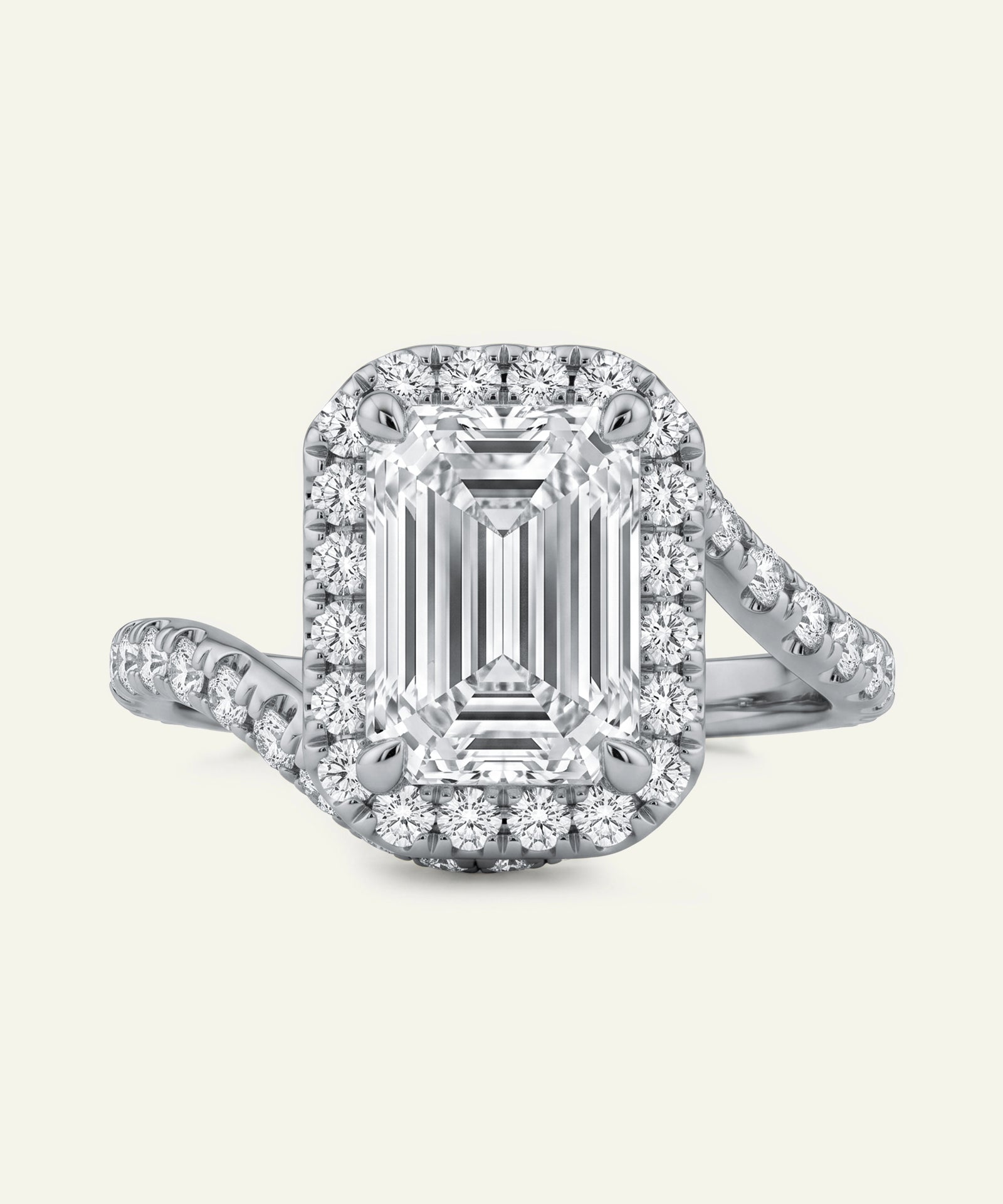 Diamond ring with emerald-cut center stone and halo on a light gray background
