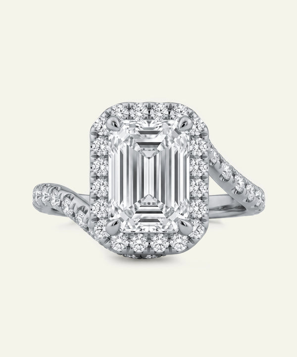 Diamond ring with emerald-cut center stone and halo on a light gray background