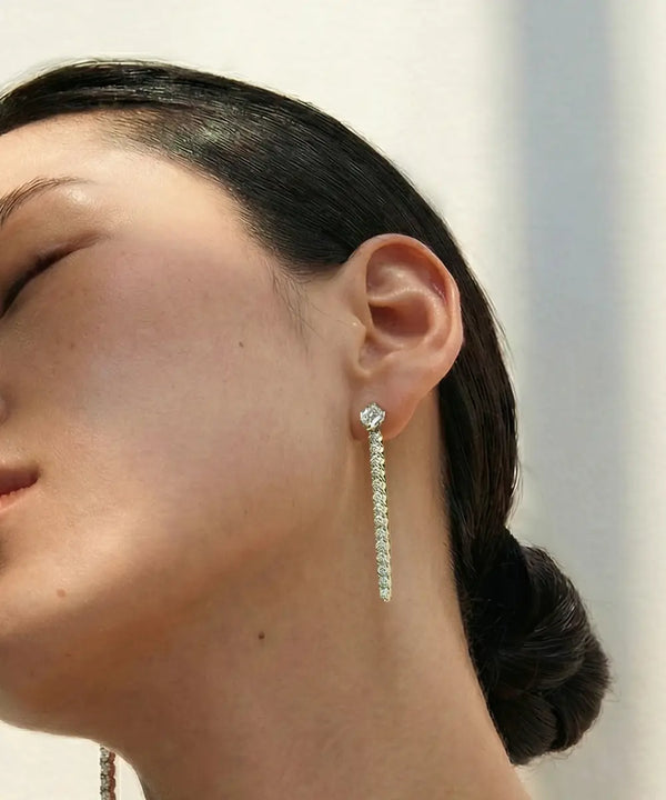 Close-up of a person wearing a diamond earring with a blurred background