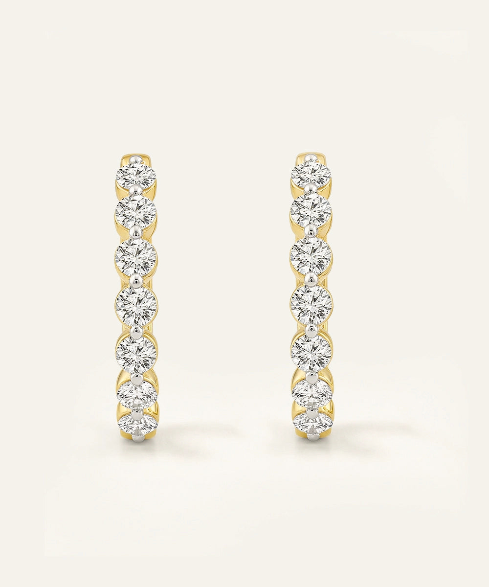 Pair of gold and diamond earrings on a light beige background