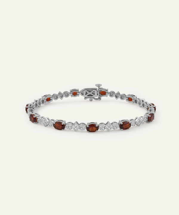 Silver bracelet with red gemstones on a white background