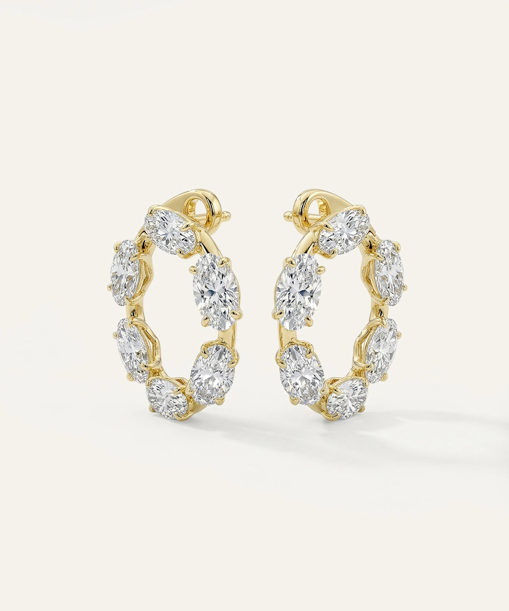 Gold hoop earrings with clear gemstones on a light gray background