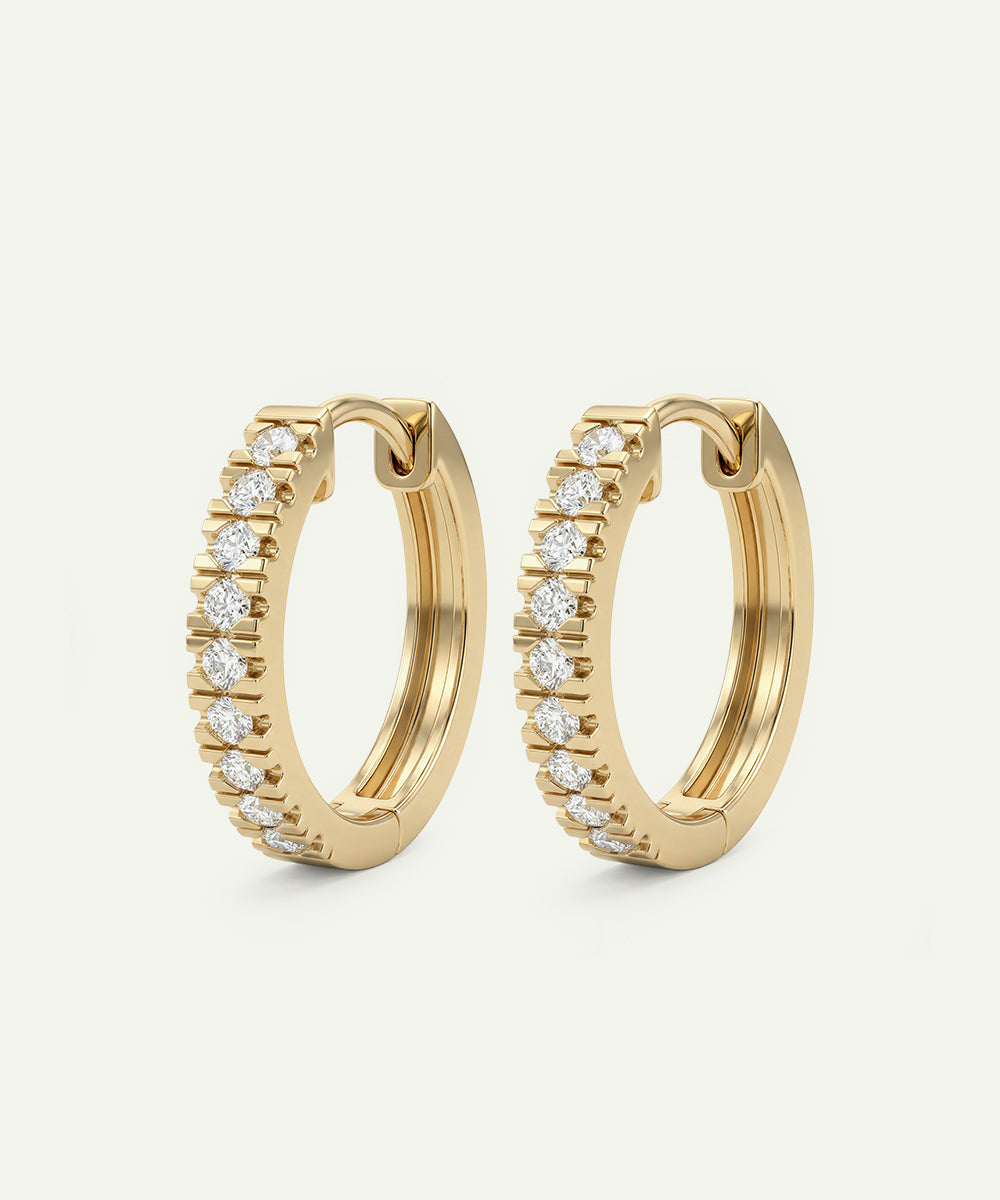 Gold hoop earrings with diamond accents on a light beige background