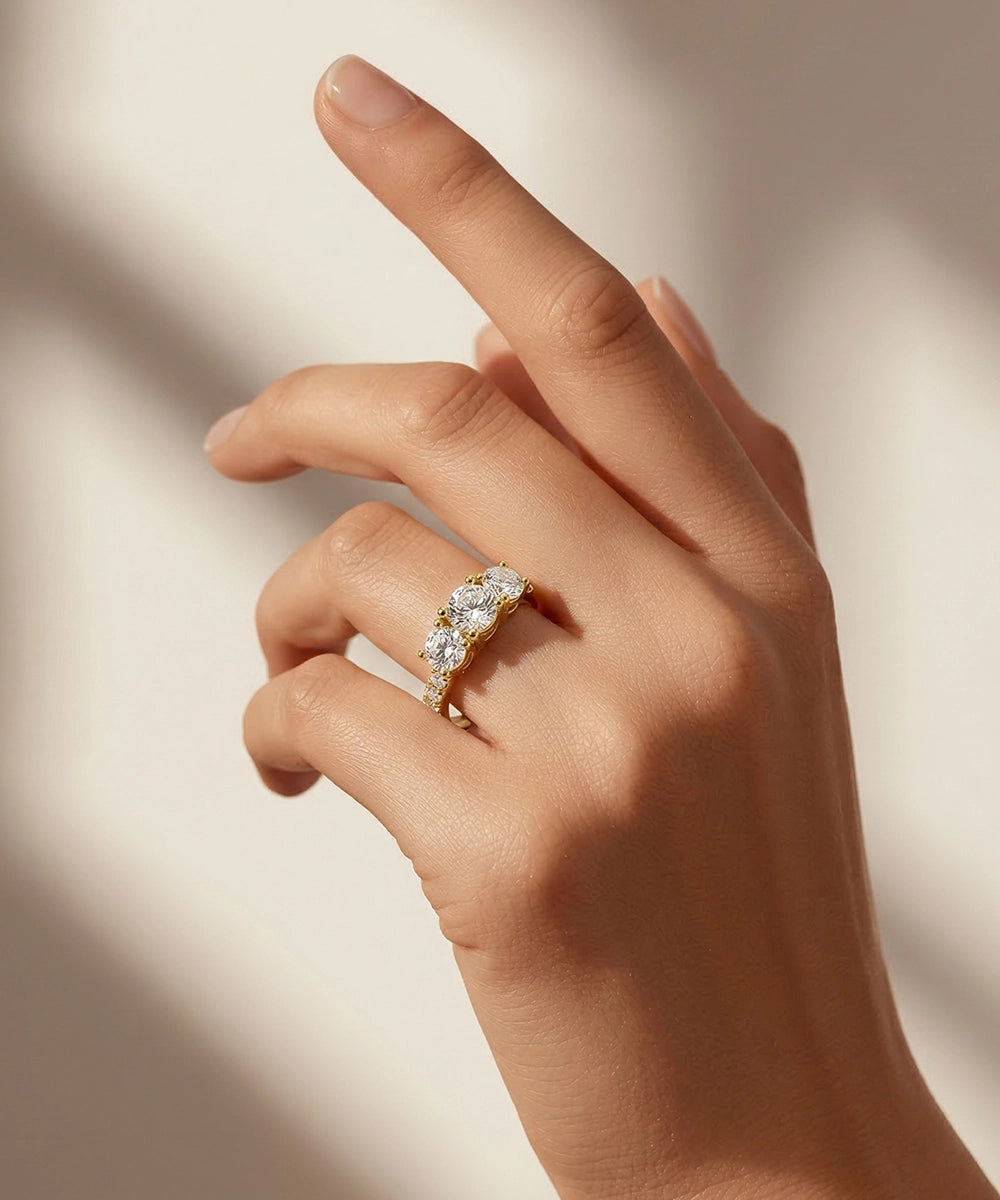 Hand wearing a gold ring with diamonds on a soft beige background