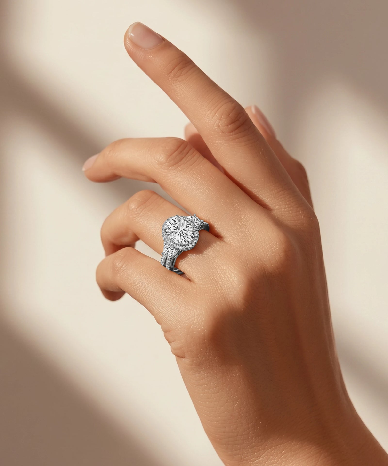 Hand wearing a diamond ring on a neutral background