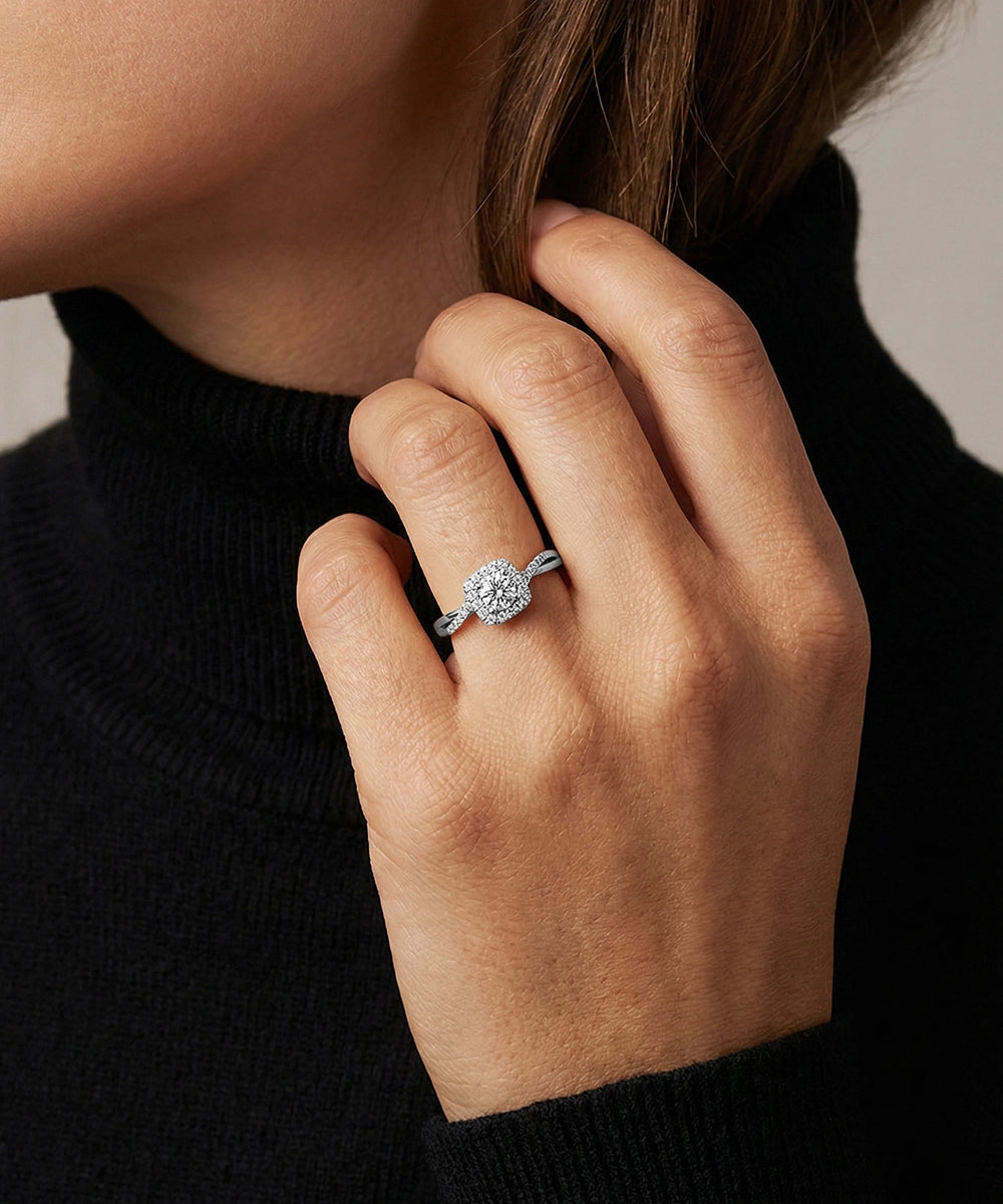 Close-up of a hand wearing a diamond ring with a neutral background