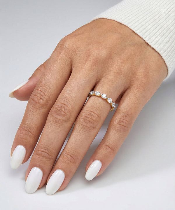 Hand wearing a diamond ring on a light gray background