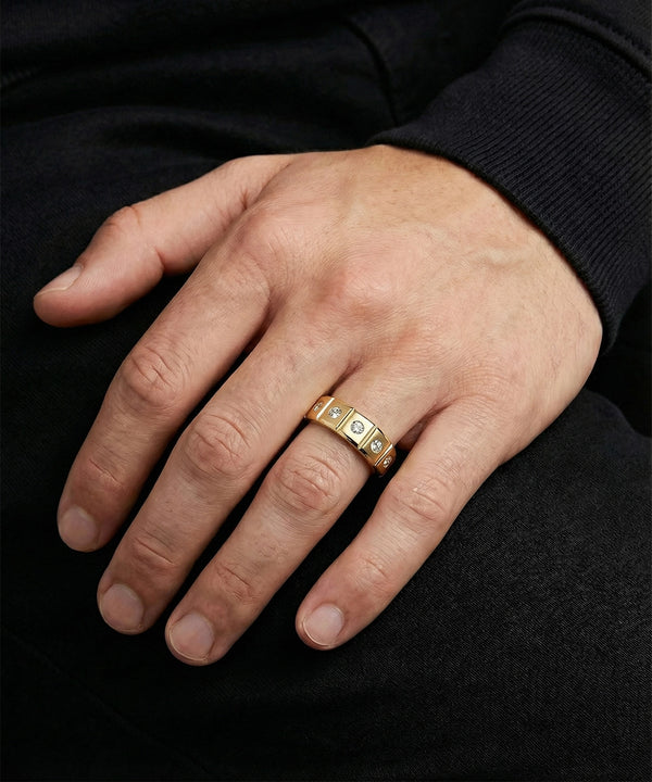 Hand wearing a silver ring with embedded stones on a black background