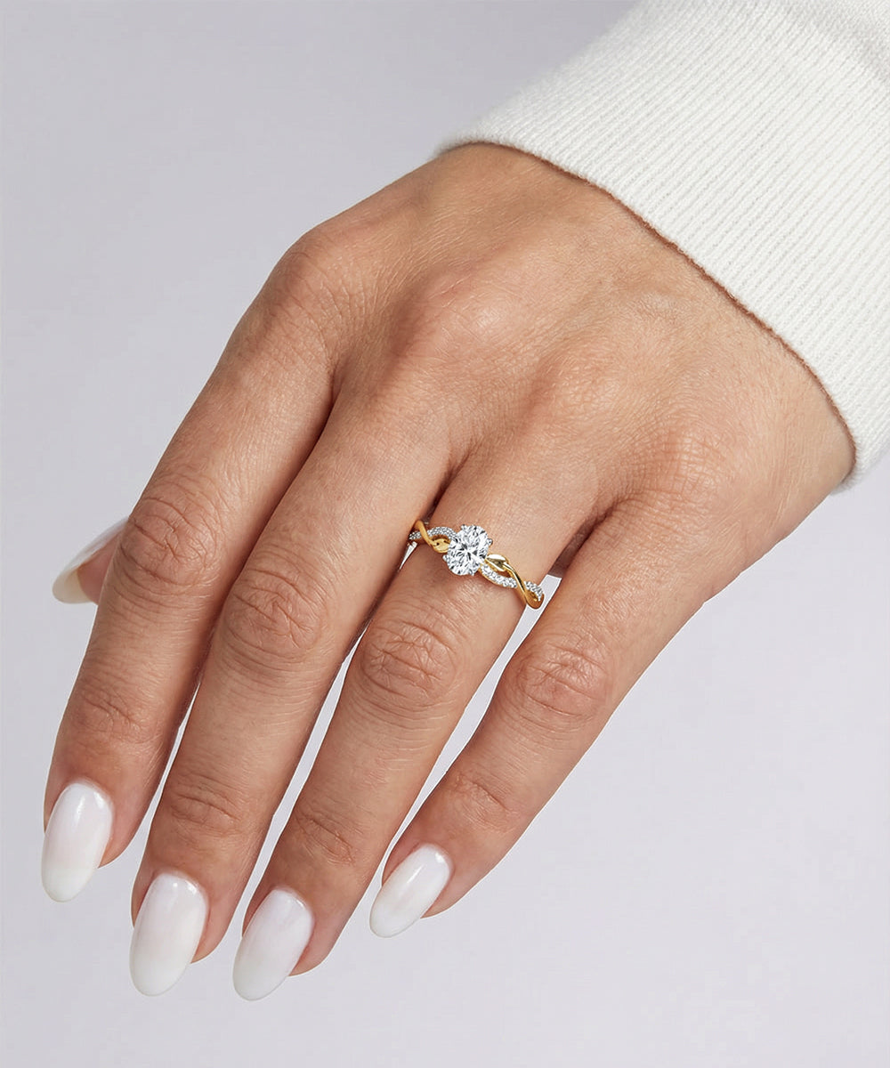 Hand wearing a gold ring with a diamond on a light gray background