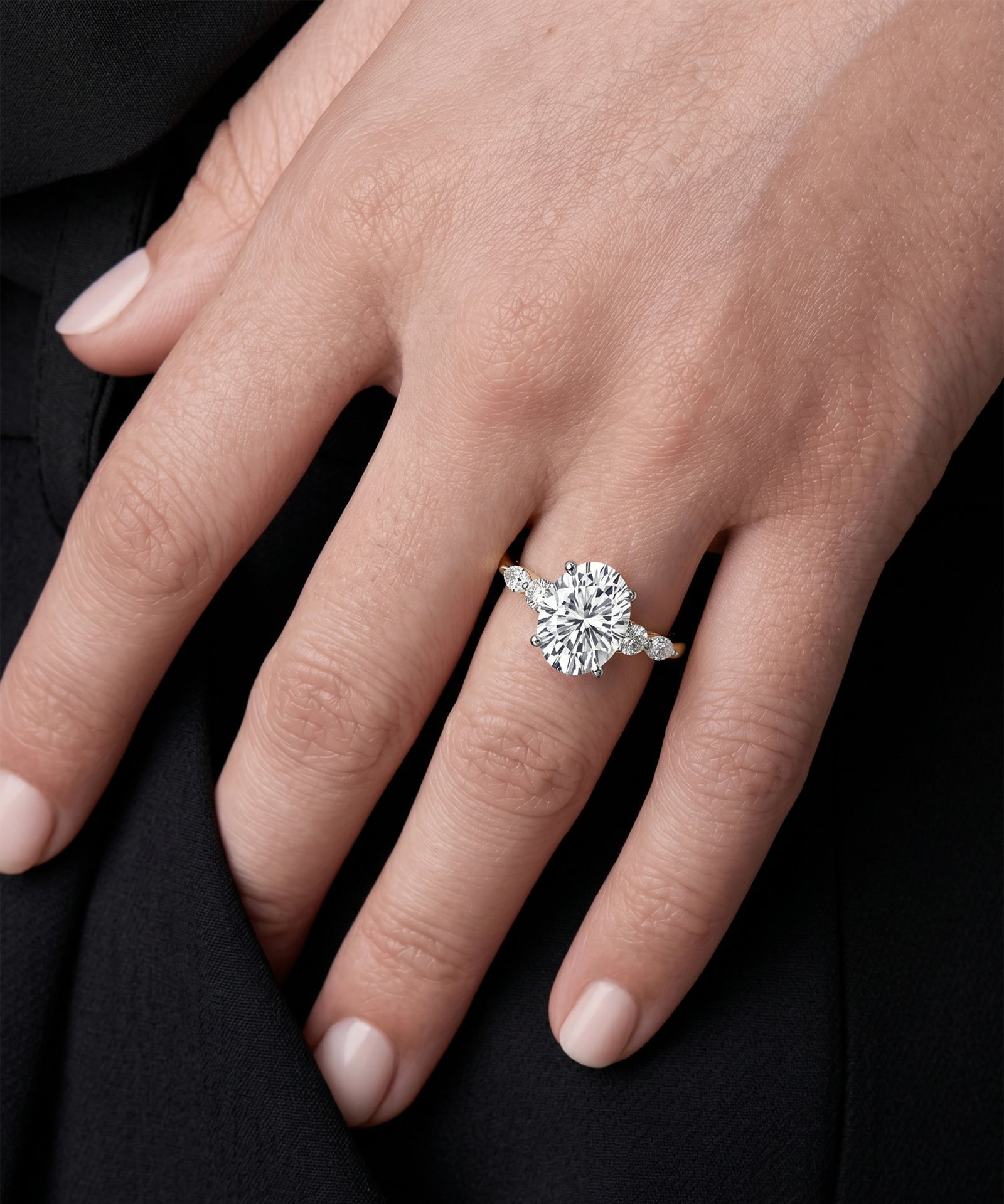 Close-up of a hand wearing a diamond ring on a black background