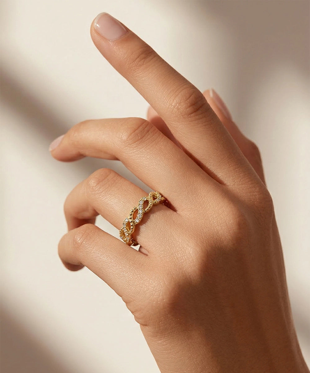 Hand wearing a gold ring on a neutral background