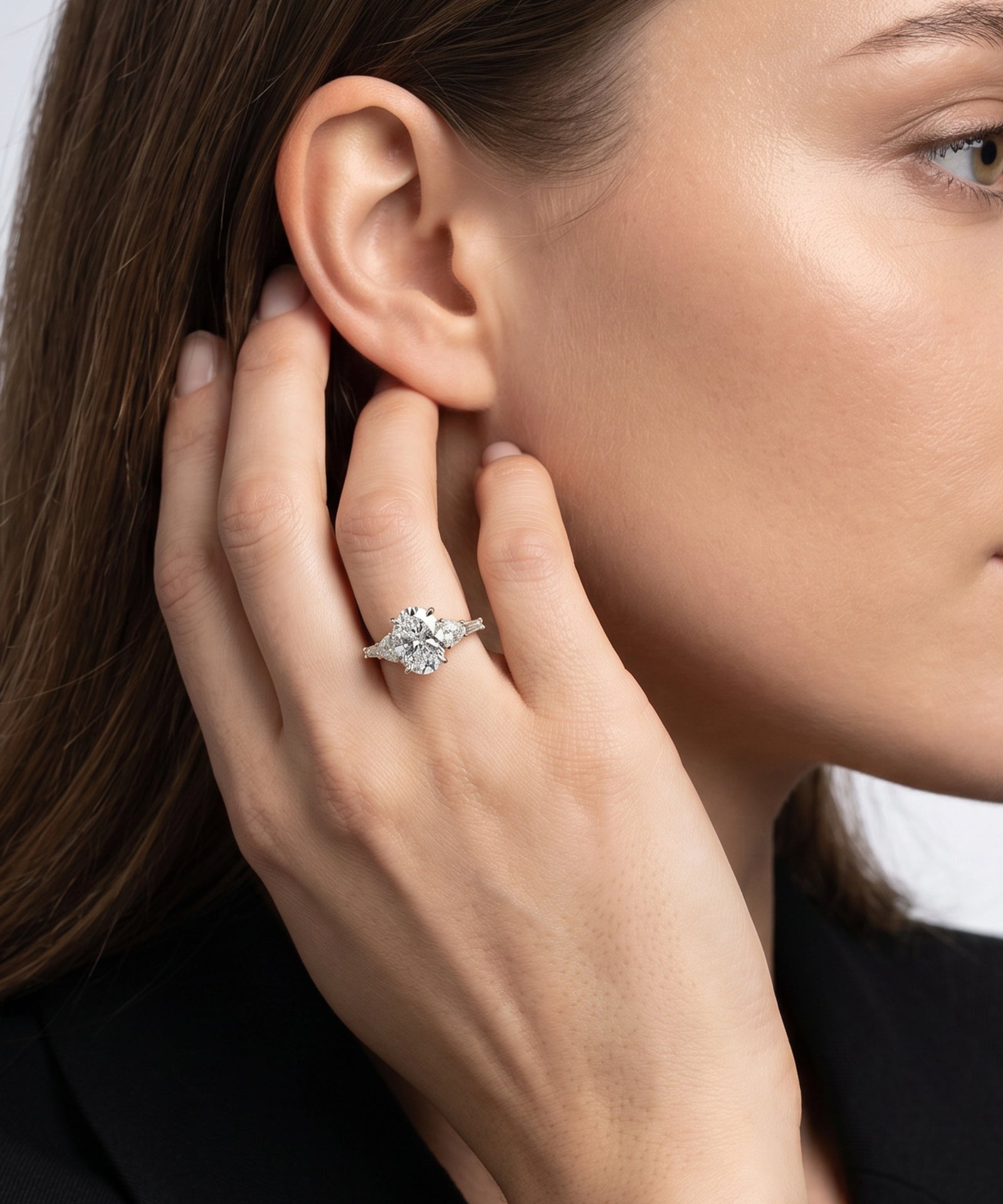Close-up of a woman wearing a diamond ring on her hand near her ear.
