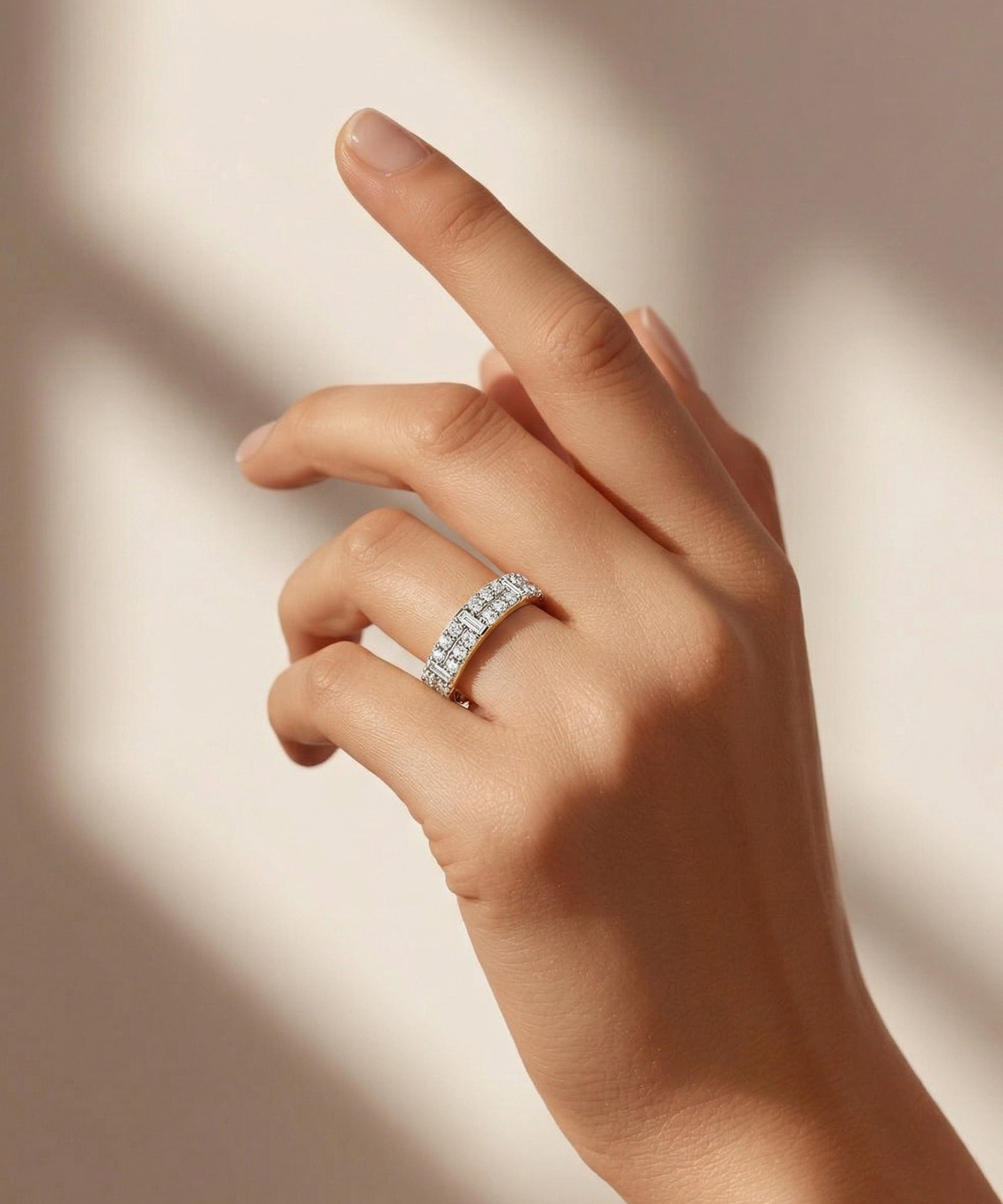 Hand wearing a diamond ring on a neutral background