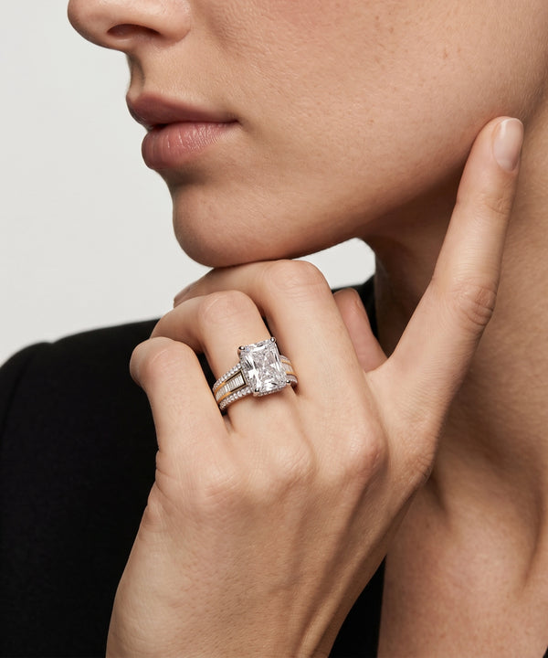 Close-up of a hand wearing a diamond ring with a neutral background