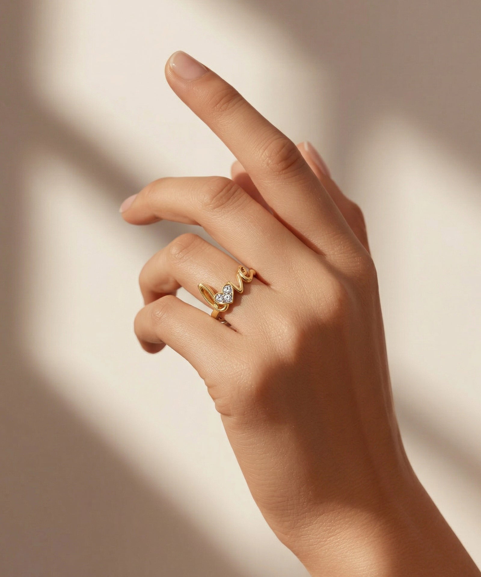 Hand wearing a gold ring with a diamond on a neutral background