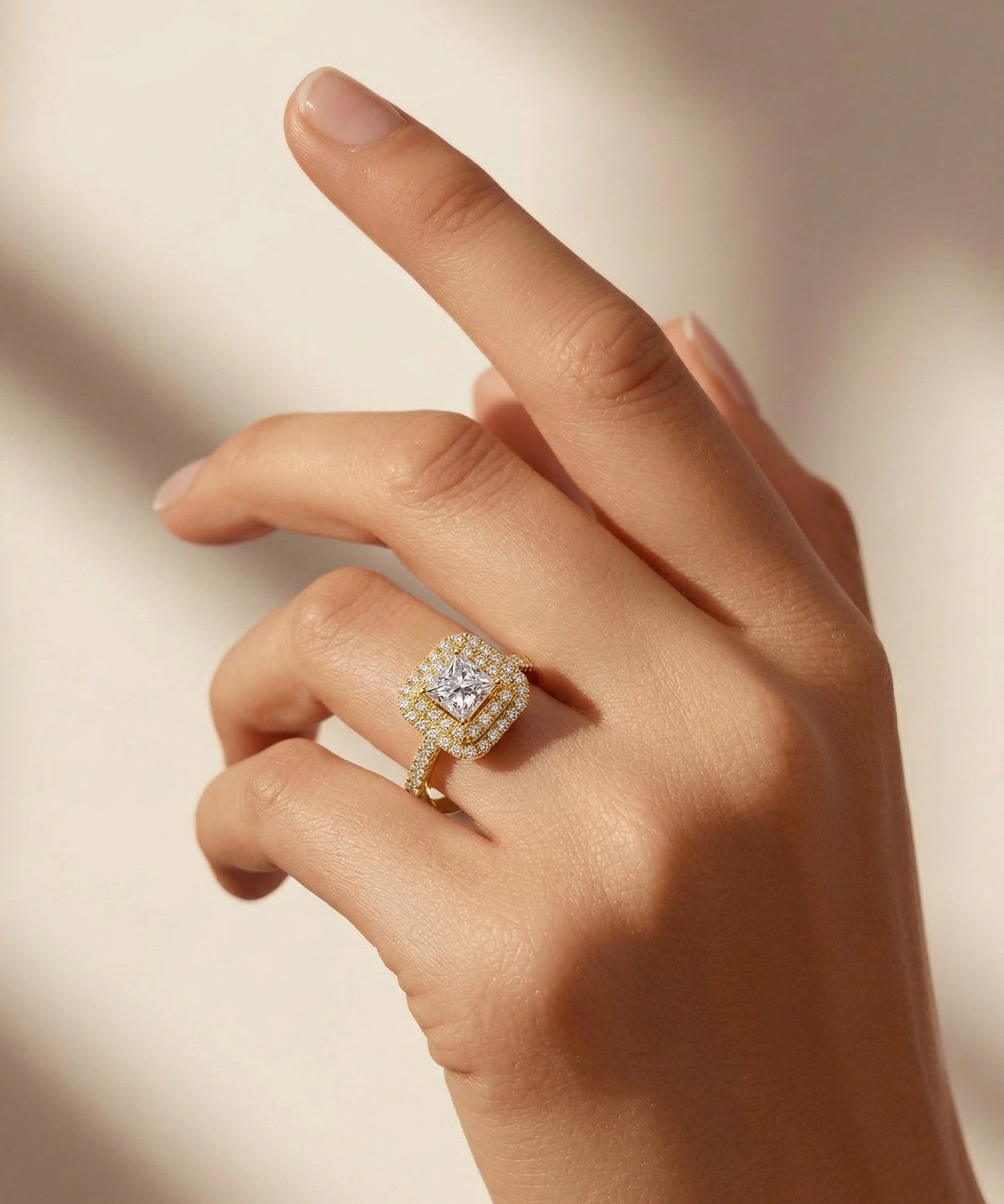 Hand wearing a diamond ring on a neutral background