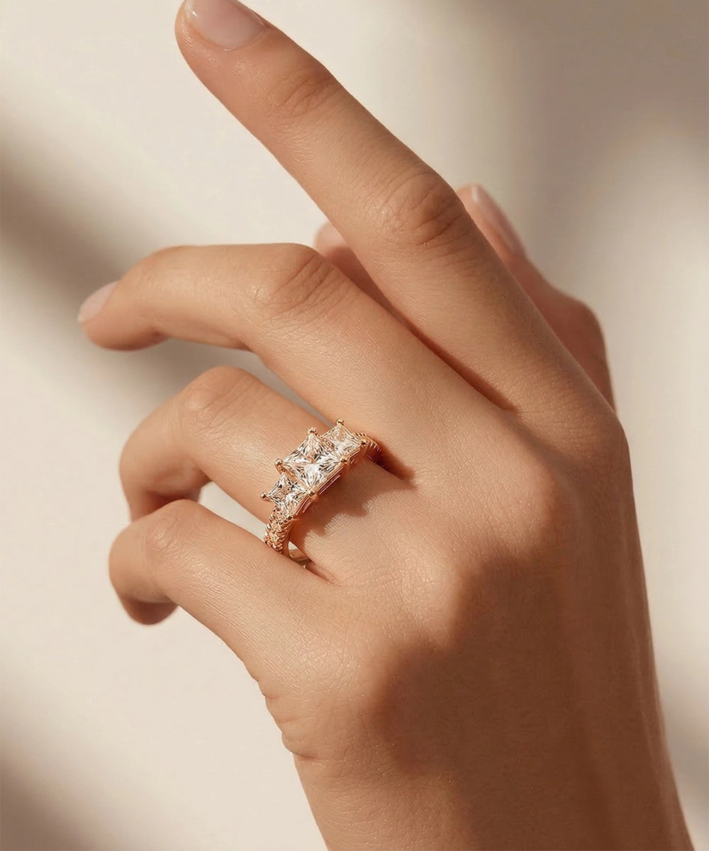 Rose gold ring with a diamond on a hand against a neutral background