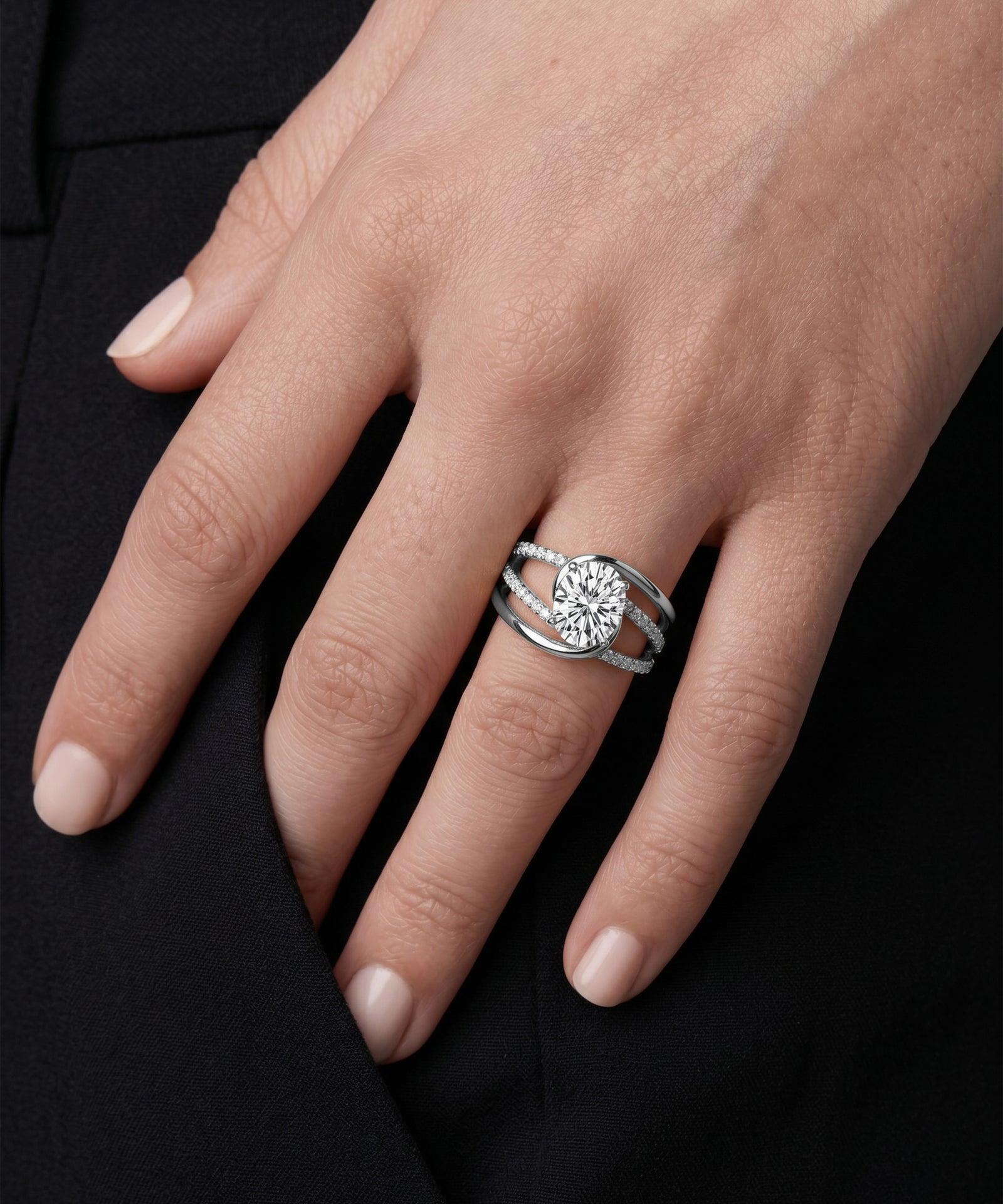 Close-up of a hand wearing a silver ring with a diamond on a black background