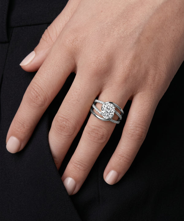 Close-up of a hand wearing a silver ring with a diamond on a black background