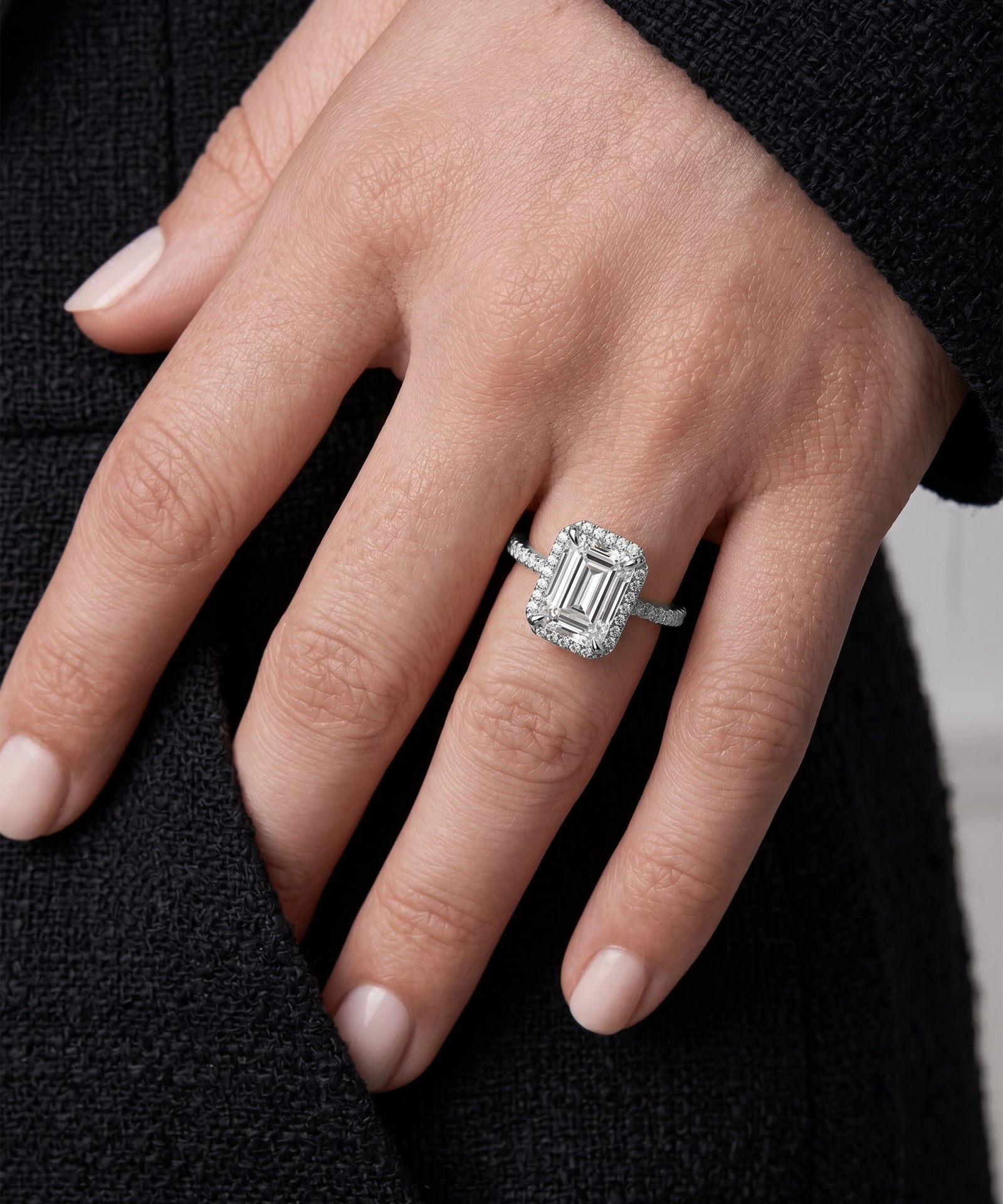 Close-up of a hand wearing a diamond ring with a black background