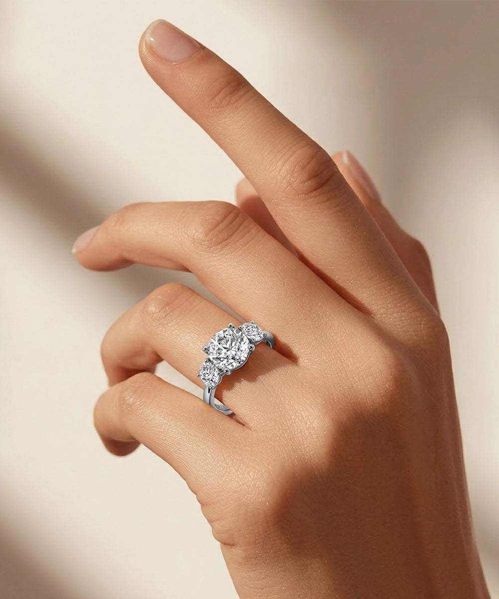 Silver ring with a pear-shaped diamond on a hand against a neutral background