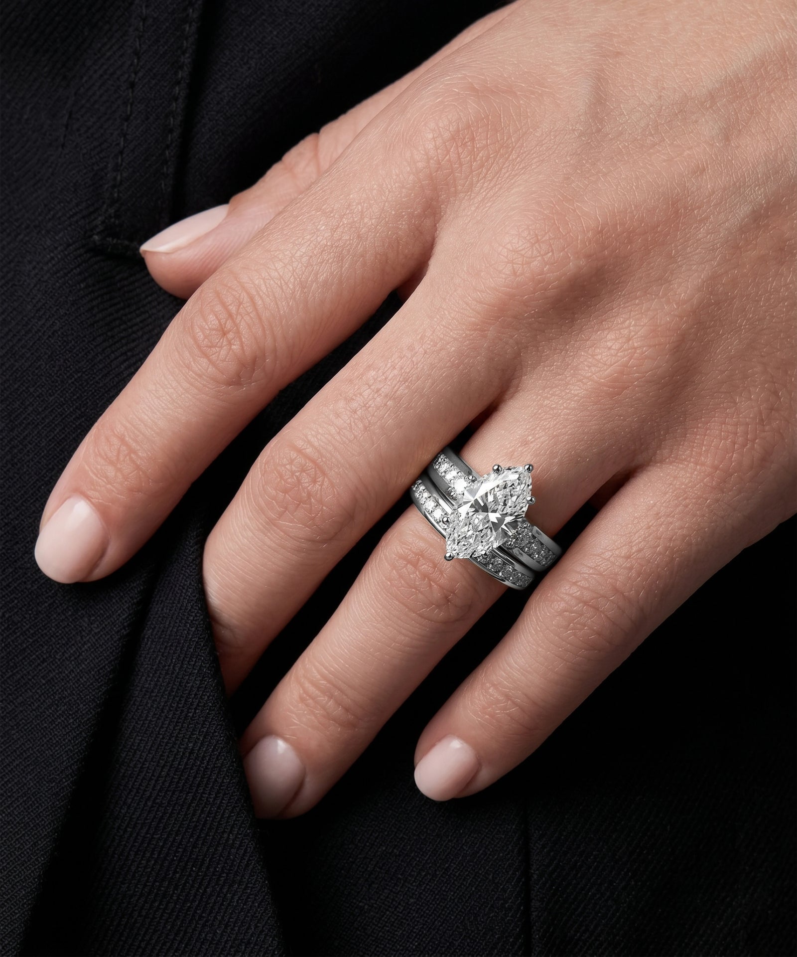 Hand wearing a diamond ring on a black background