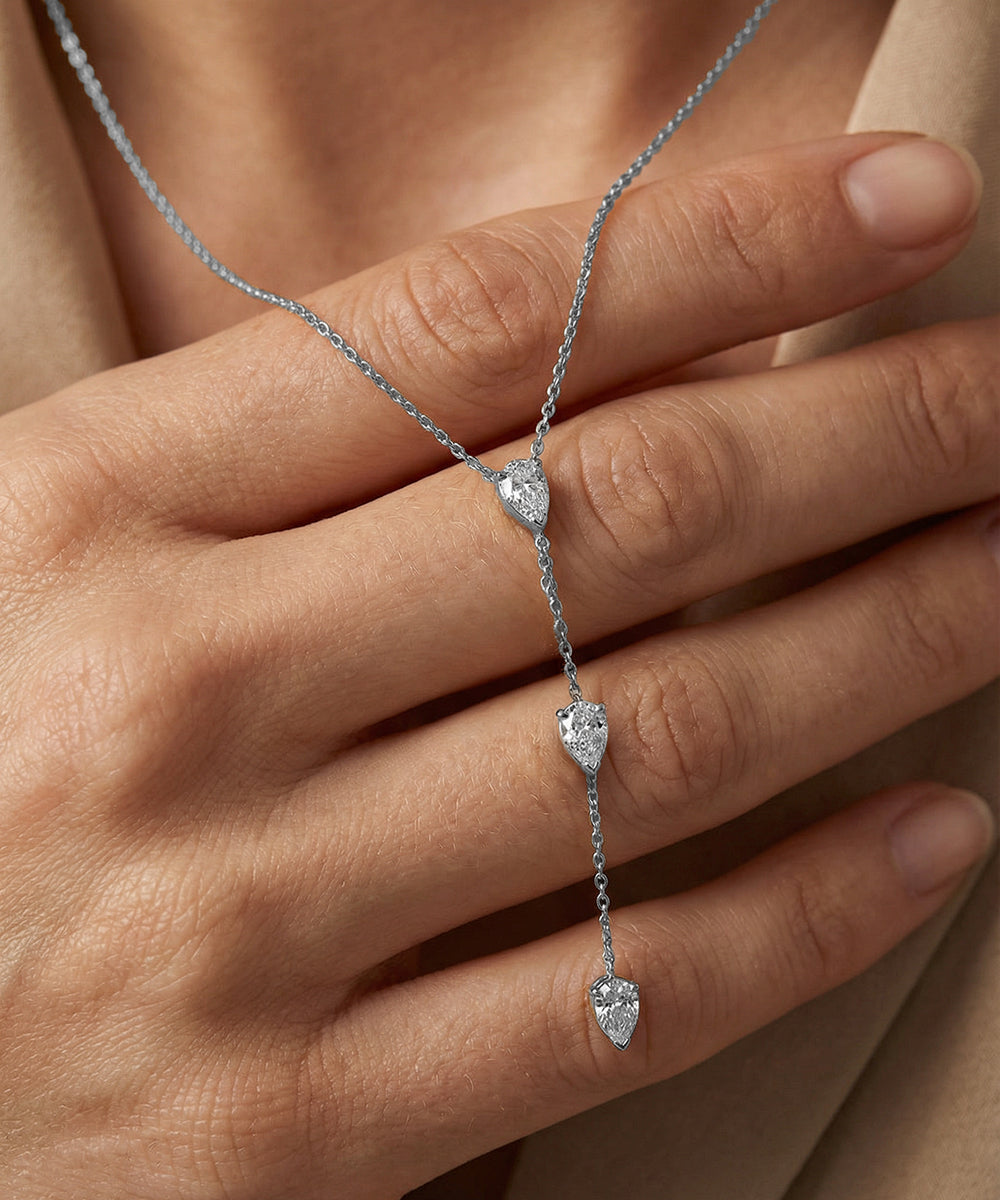 Silver necklace with heart-shaped pendants on a hand