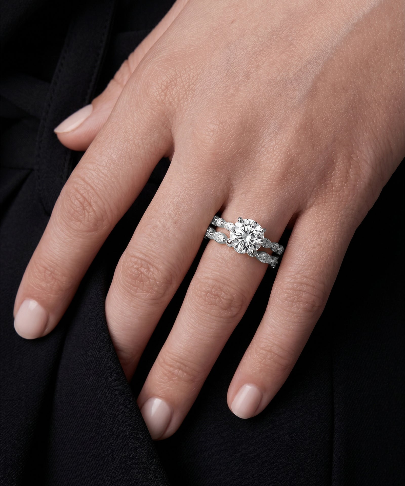 Close-up of a hand wearing a diamond ring on a black background