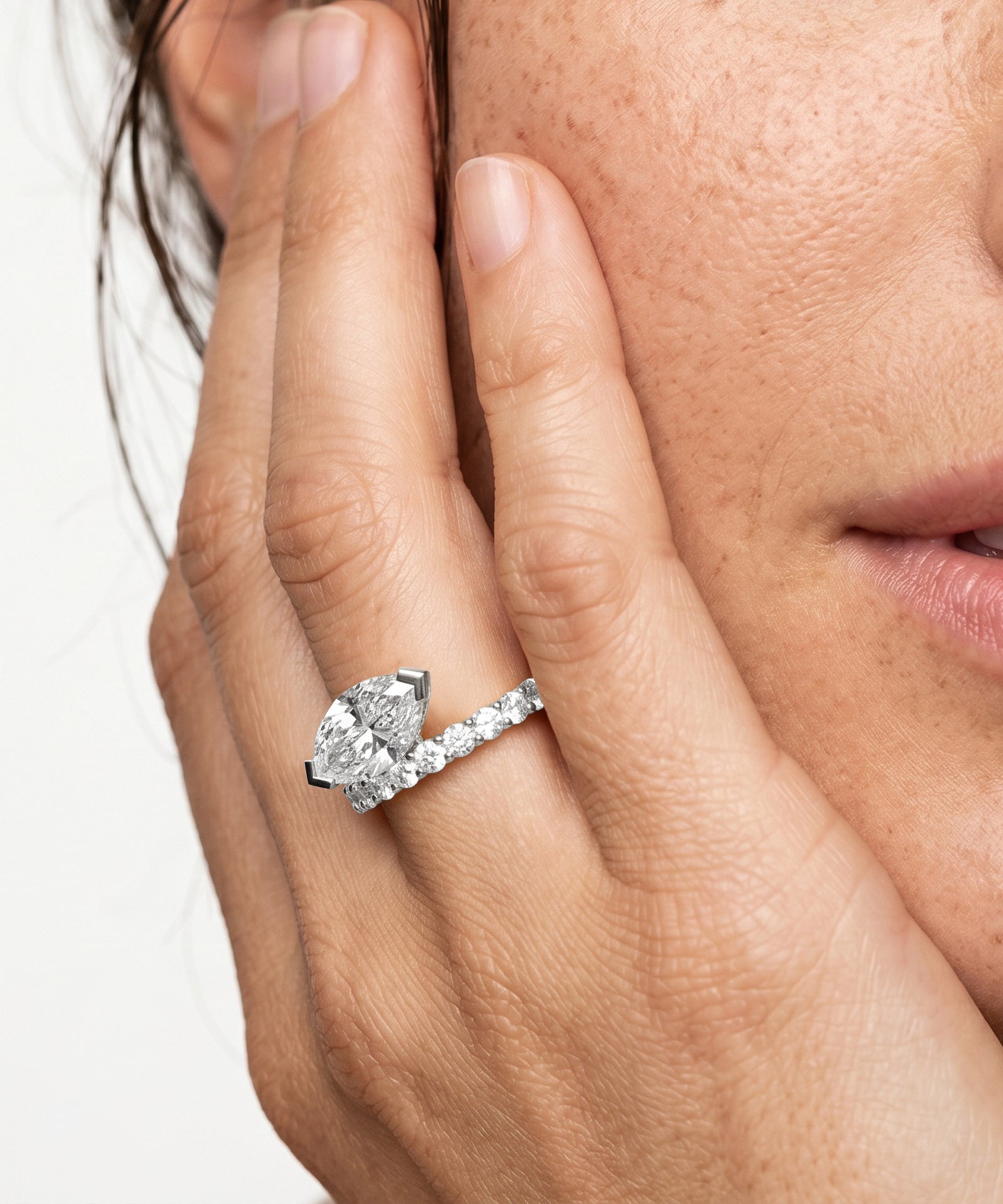 Close-up of a hand wearing a diamond ring on a white background