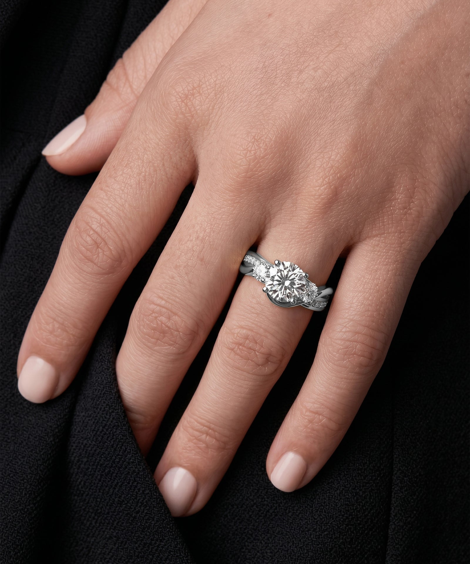 Close-up of a hand wearing a diamond ring on a black background