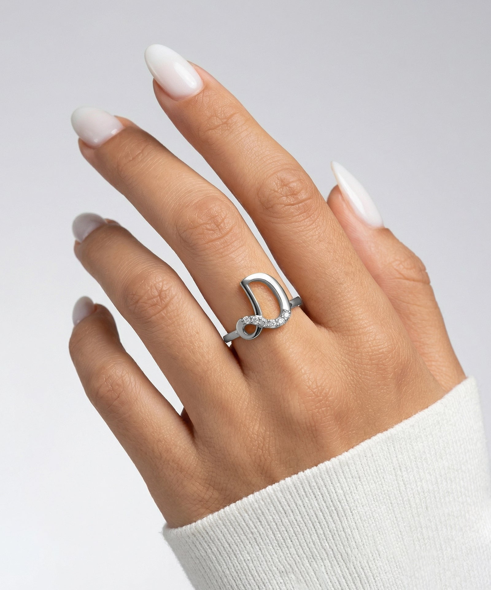 Hand wearing a silver ring with a white background