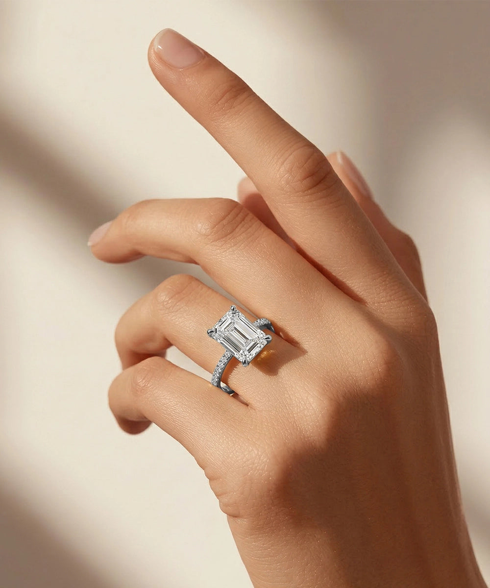 Hand wearing a diamond ring on a neutral background