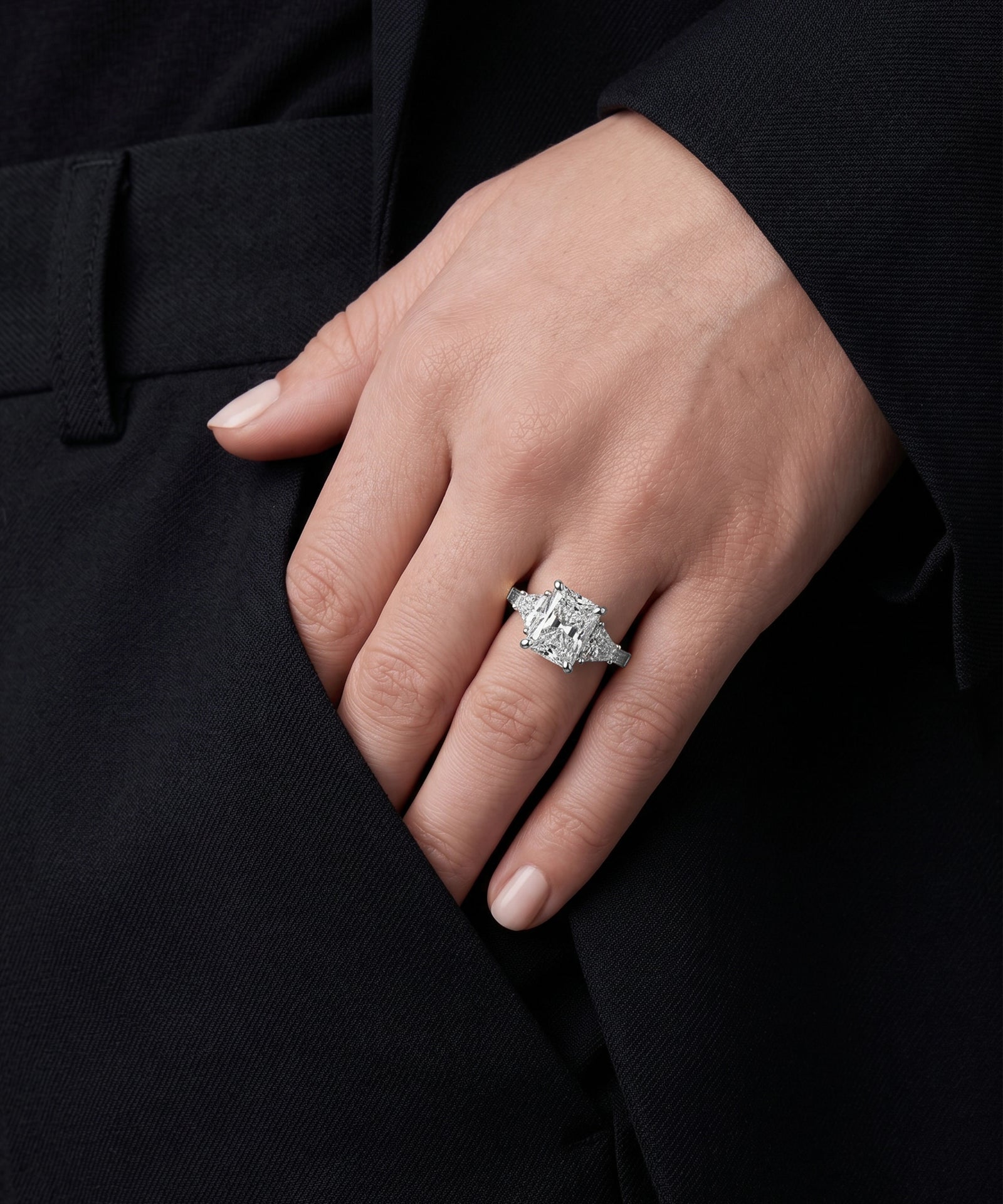Hand wearing a diamond ring on a black background