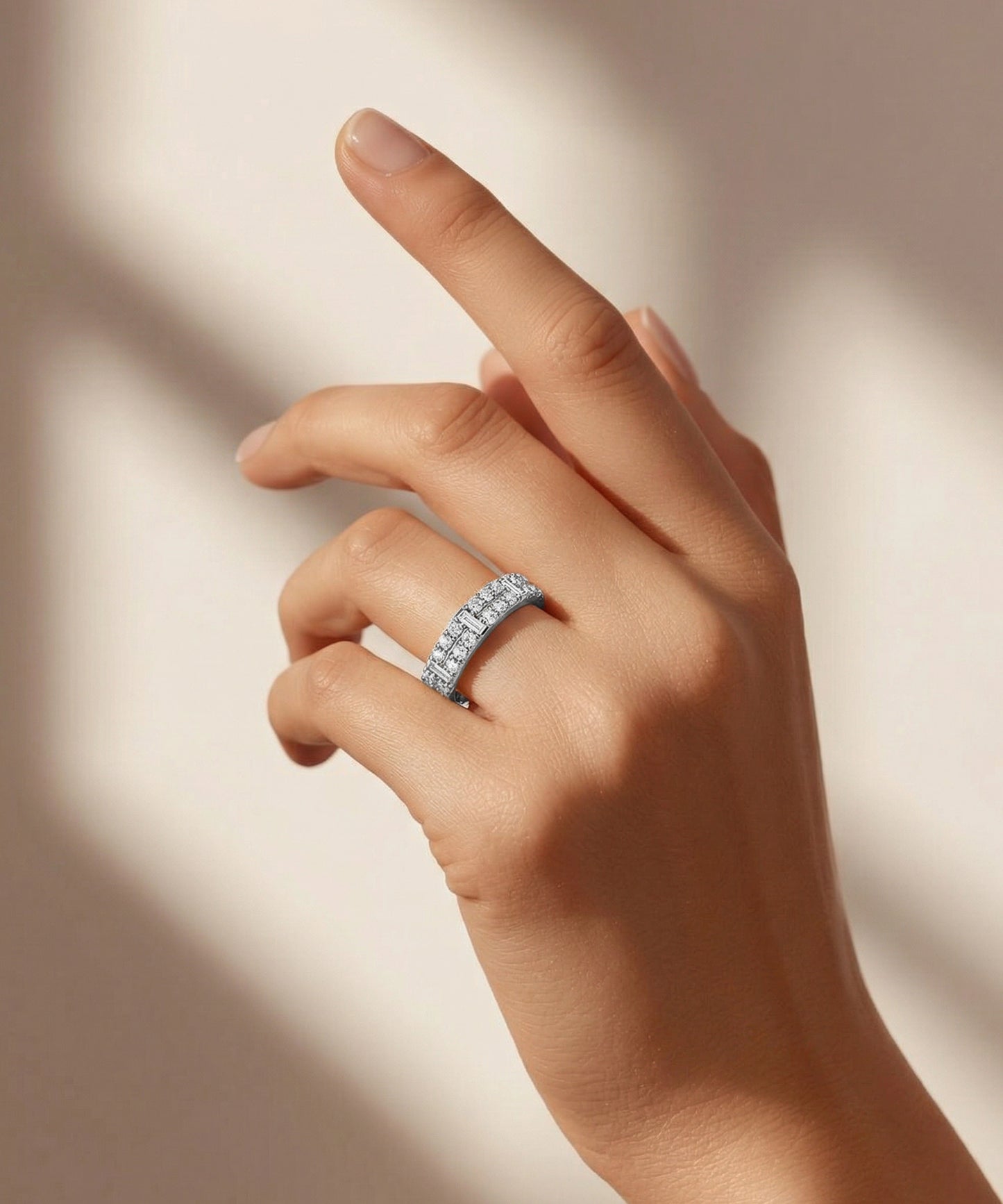 Hand wearing a diamond ring on a neutral background